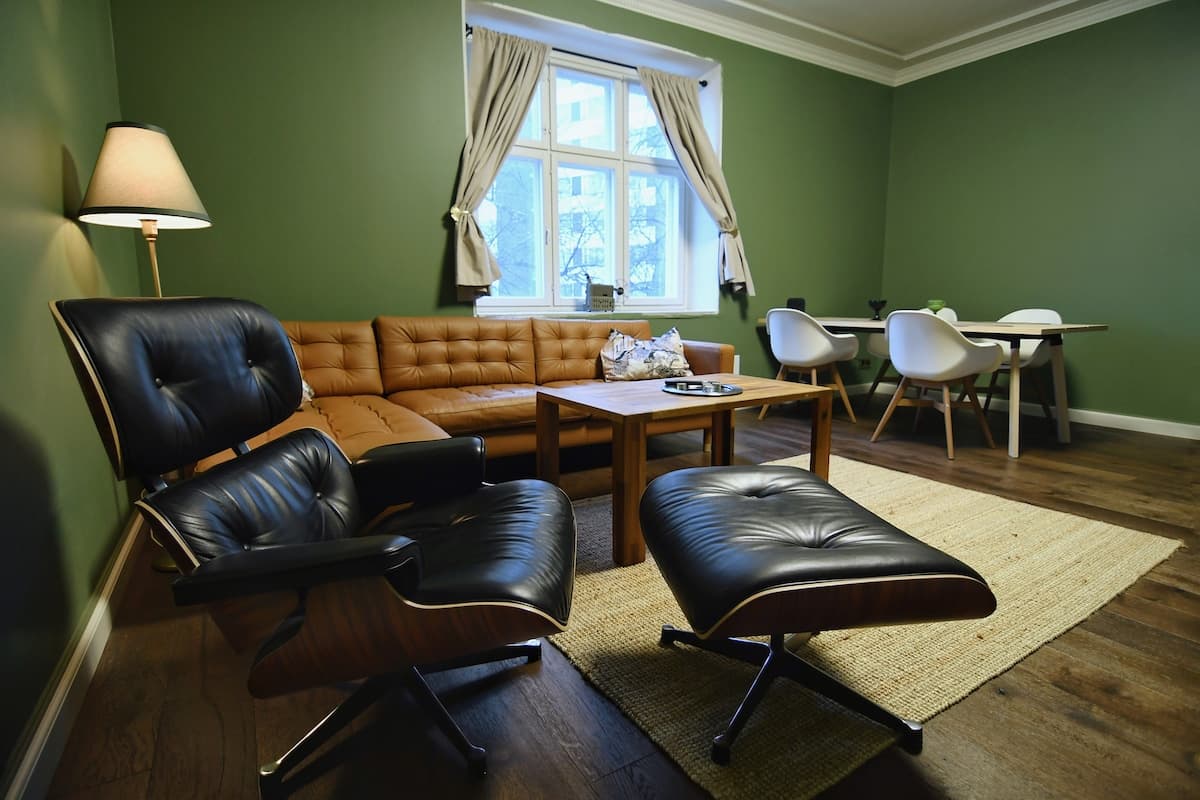 Living room with an Eames lounge chair, a tan leather sofa and green walls